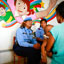 Duas policiais mulheres em frente a um mural colorido, falando com uma mulher de costas para a câmera