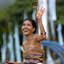 Mulher sorridente com vestido colorido joga flores para o ar